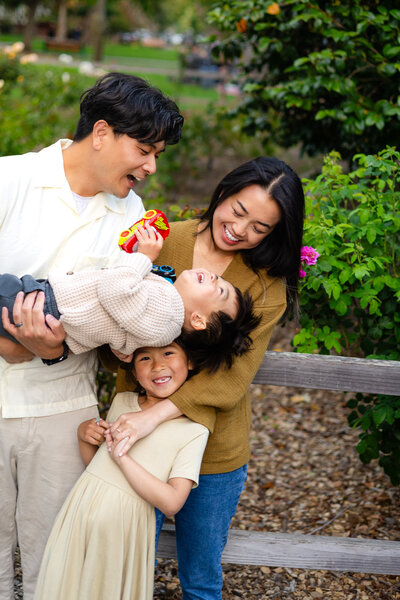 Family laughing together with a toddler held upside-down, captured joyfully by Ellobelle Photography Family Photographer