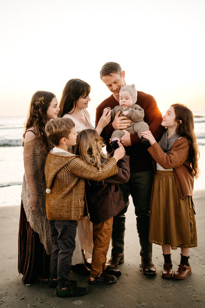 Family wearing coordinating outfits in a golden field. 
