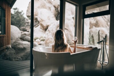 Woman in luxury bath drinking wine at sunset