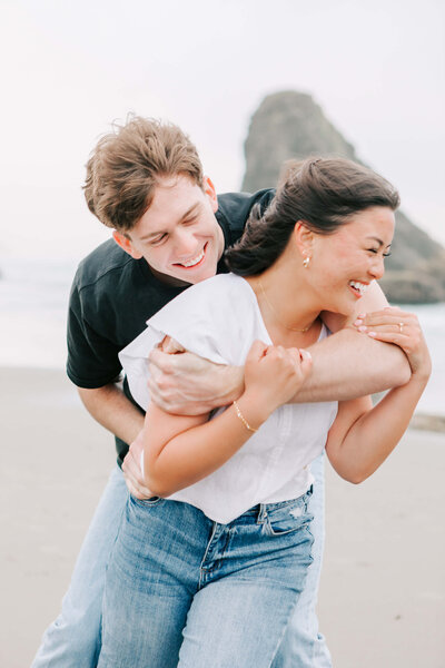 An engaged couple play on the beach during engagement photos at the Oregon Coast