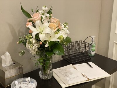 funeral sign in book flower arrangement with peach roses white lilies and green hydrangea 