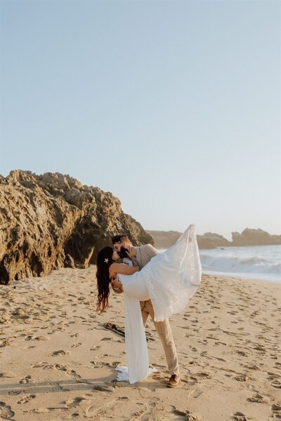 groom holding and dipping bride on a beach