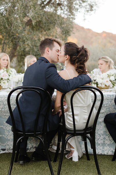 Bride and groom kissing at their wedding reception table