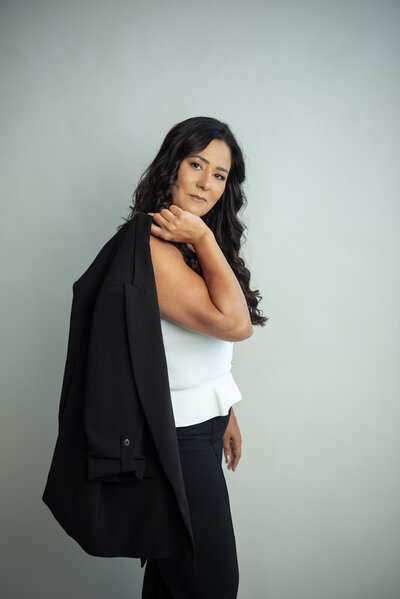 Portrait of Asmahan, a strategic online business manager, sitting confidently in a neutral dress against a stone backdrop