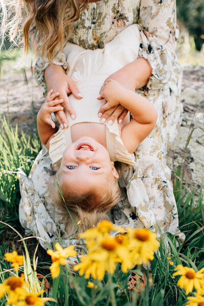 mom holding baby girl facing outward and smelling her head