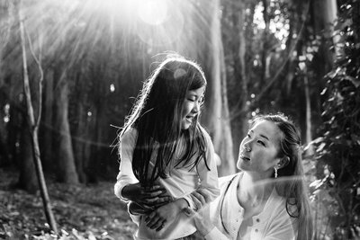 A black and white photo of a mother and young daughter connecting in the Presidio