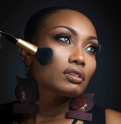 Beauty portrait of African woman with makeup brush by Portrait Photographer in Austin