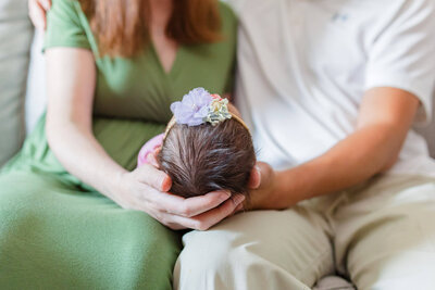 A baby girl held in her parents' laps.