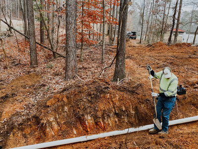 man-digging-ditch-in-woods-to-place-drainage-system