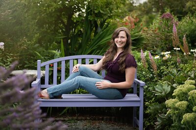 Young woman in purple blouse sits on a park bench