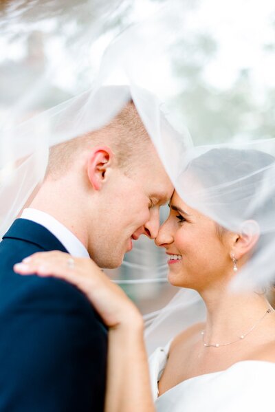 Bride and groom eskimo kiss under veil at Downtown Charlottesville wedding