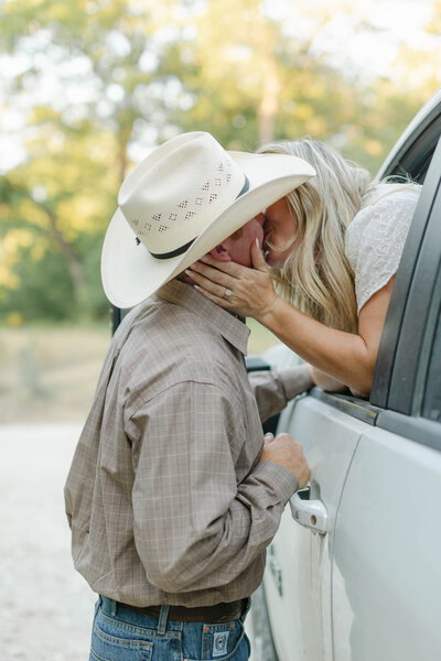couple kissing in cowboy hat during engagement session