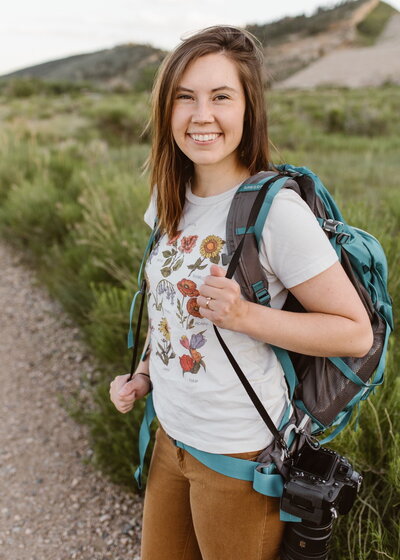 Bailee, Colorado adventure elopement photographer with Alpine Vows, smiling with hiking backpack and camera gear ready to capture couples in Colorado.