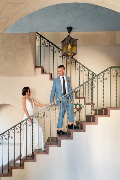 Groom leading bride up stairs at their wedding at The Prado in Balboa Park
