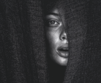 Close-up black and white portrait of a woman partially veiled, symbolizing emotional depth and personal transformation.