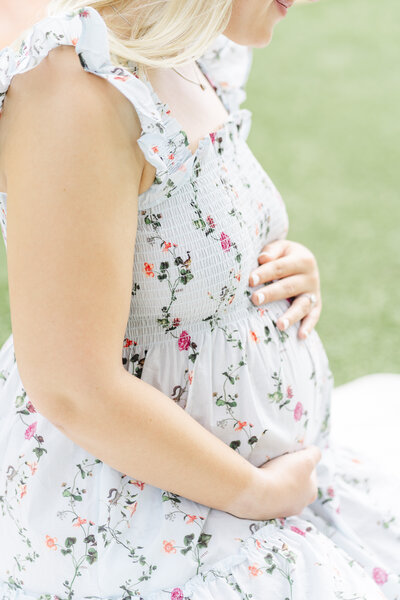 Photographer Round Rock TX | A pregnant mother sits on a white blanket in the courtyard of Woodbine Mansion in Round Rock, TX.