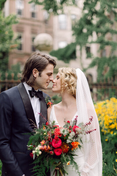 Bride and groom sharing an intimate moment, almost kissing, in a lush New York City garden during their wedding