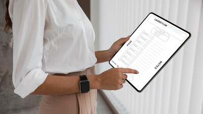 A student is holding a tablet displaying a page from a 'Ladder Flow Intermediate' yoga sequence with various poses listed under 'POSE' and 'NOTES,' indicating a structured yoga class plan.