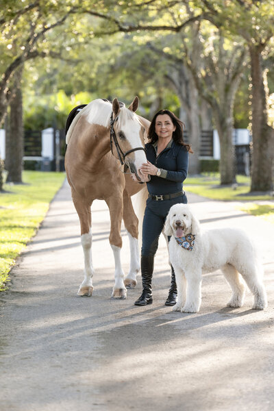 photo of a woman with her palomino horse and poodle dog