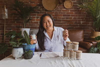 a woman smiling and seated at a table surrounded by Live Long and Plant products
