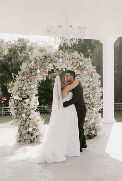 A couple, likely a bride and groom, are ecstatically celebrating during what appears to be a wedding reception or event.