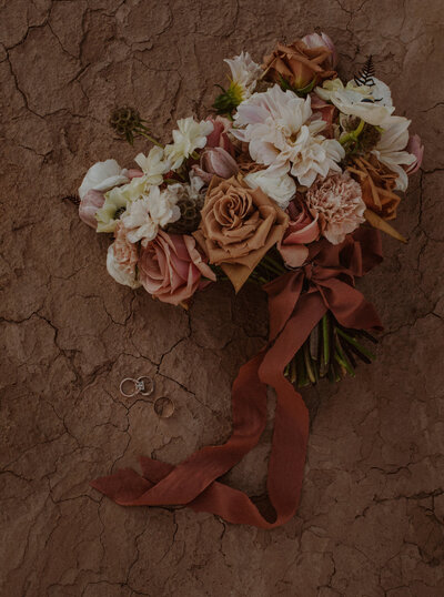 Elopement bouquet lays on the cracked desert ground in Moab