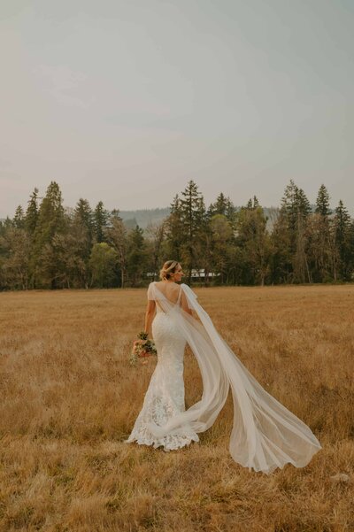Bride walking away with her veil blowing in the wind in Oregon wedding