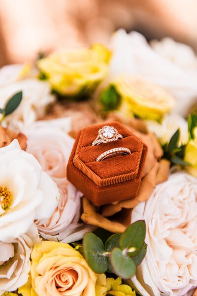 closeup of wedding rings bands in velvet box sitting on bouquet of flowers at Aldea Weddings in the Woods in Flagstaff