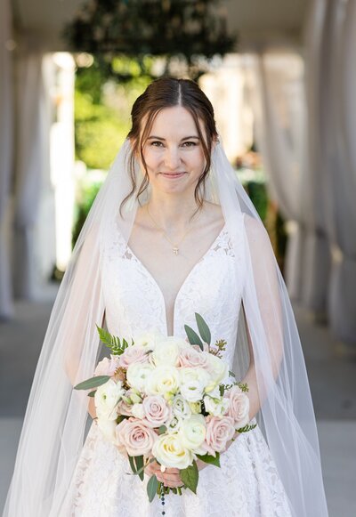 bride smiling in her wedding dress and holding a bouquet