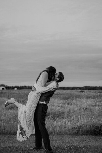 Bride & groom having romantic kiss during their backyard tent wedding in Manitoba