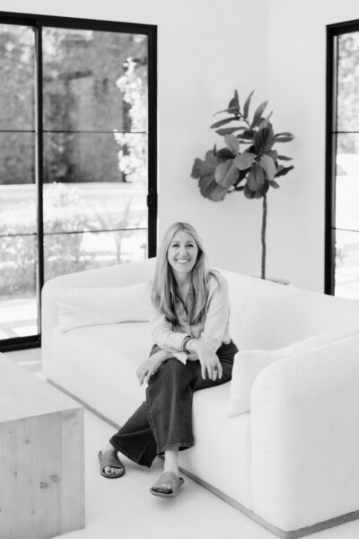 Portrait of Suzanne Karp, owner of Little Palm Photography, sitting in her natural light studio. A friendly and welcoming image capturing her warmth and personality.