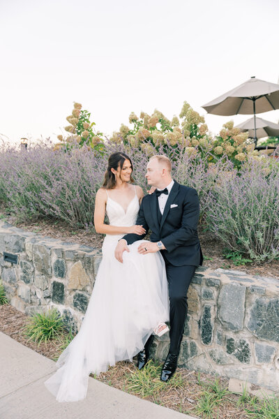 Wedding couple sitting on a wall at Virginia golf course wedding.