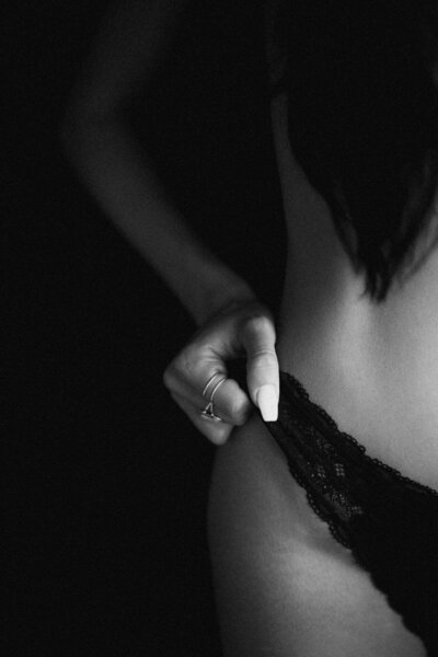 A close-up of a woman adjusting her black lace lingerie during a Boudoir Phoenix photoshoot, highlighting elegance and intimate detail.