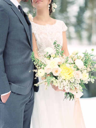 Bride and groom embrace while holding lush bouquet