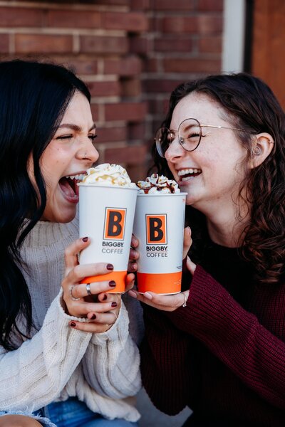 Friends drinking Biggby Coffee on the steps of a building. 