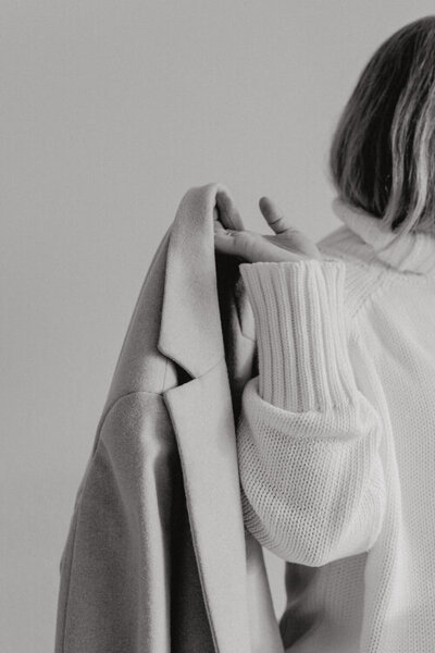 detail ruky ženy ve svetru, která dží kabát