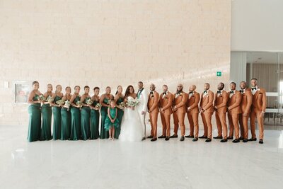 A group of bridesmaids and groomsmen in green suits.