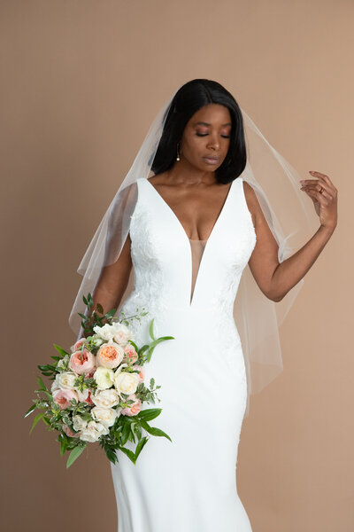 Bride wearing a short veil with waterfall shape and holding a bouquet