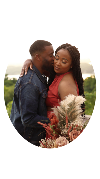 Black couple kissing near the mountains during their styled anniversary session with boho flowers