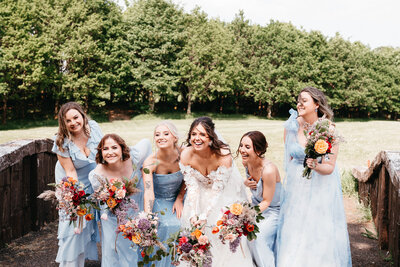 Bride and her bridemaids crouching with their flower bouquets at Castle Dargan in Sligo, Ireland