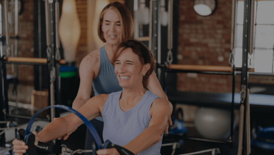 woman giving hands on assistance to a client in a pilates class 