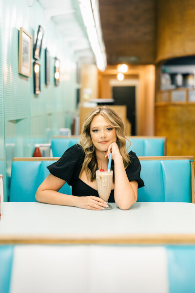 girl sitting with a milkshake in a retro diner