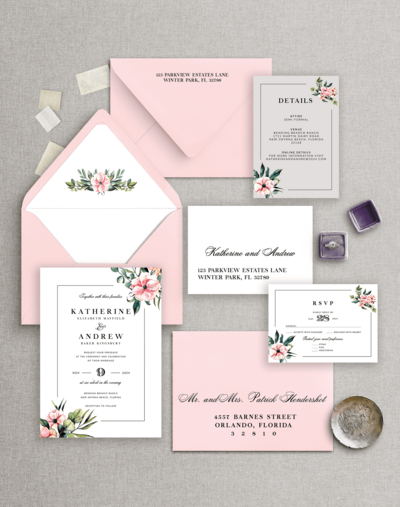 Flat lay of a pink and white floral wedding invitation suite