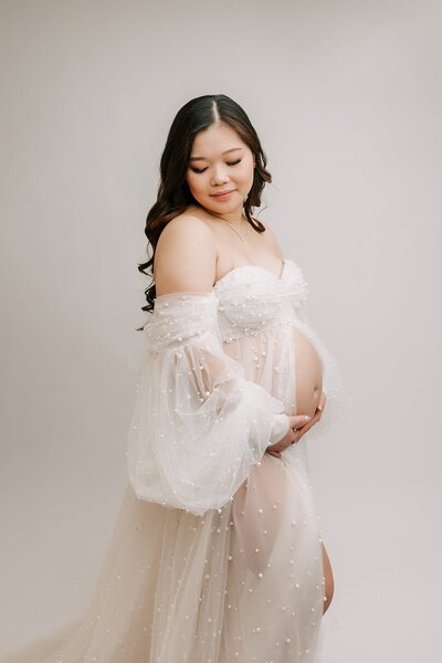 expecting mom in tan dress in front of Wahclella Falls, near Portland, Oregon for maternity photography session with Ann Marshall Photography