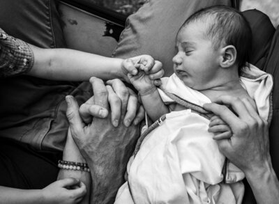 A family holds hands with the newest member of their family a little girl.