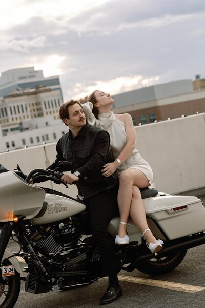 A couple sits on a motorcycle looking off into the distance