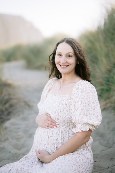 Senior portrait session at Pismo Beach during golden hour, featuring a young woman in a black dress posing in the ocean and on the wet sand. Soft natural light, ocean waves, and a dreamy beach backdrop create a timeless and elegant senior photo shoot.