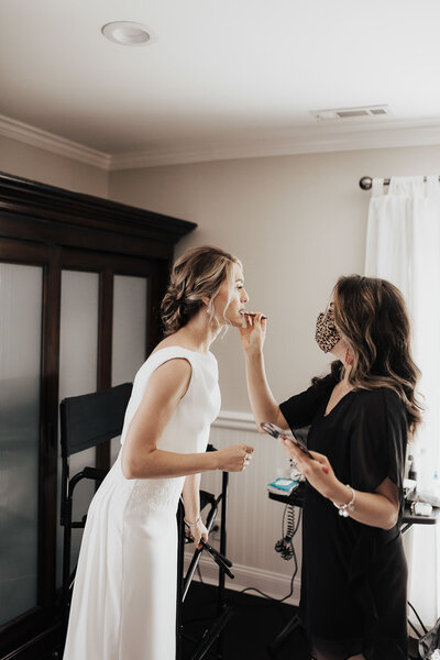 Bride getting final makeup touch by makeup artist