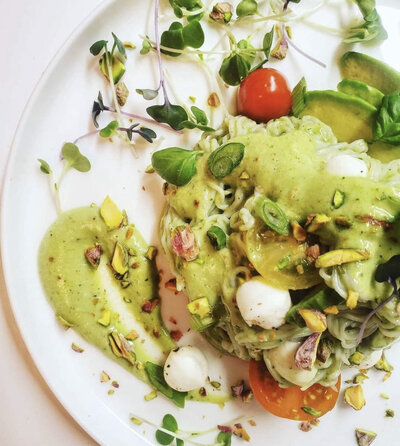 Farm to table meal topped with microgreen, tomatoes, and a bright green sauce