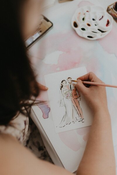 Close-up of Stephanie Anne Illustration's process, drawing a custom wedding couple sketch with delicate watercolor techniques